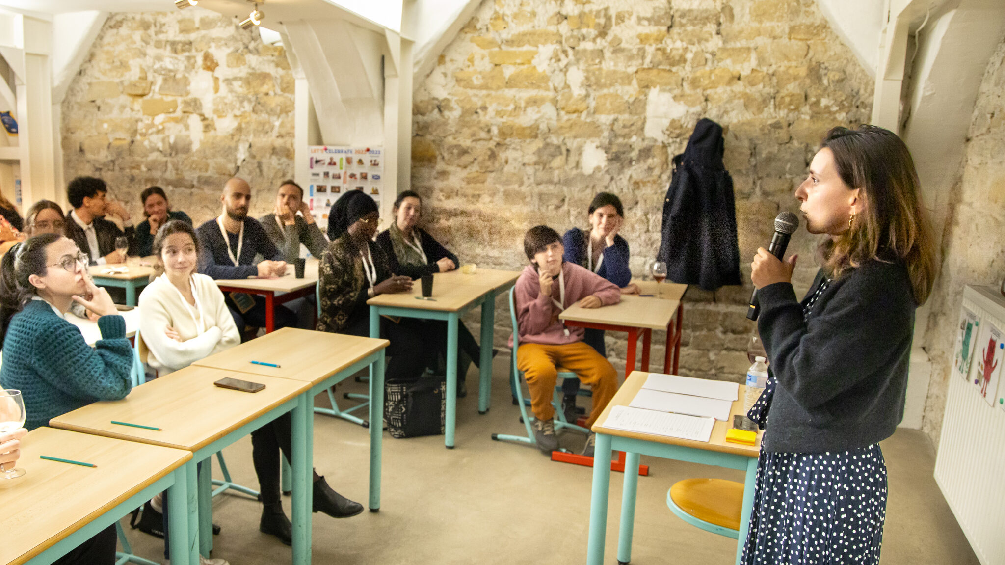 Une enseignante parle devant des élèves attentifs.